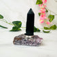 obsidian and lepidolite ring holder on white marble with leaves and flowers