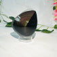 raw rainbow obsidian with polished front sitting on white marble with vines and flowers