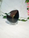 raw rainbow obsidian with polished front sitting on white marble with vines and flowers