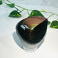 raw rainbow obsidian with polished front sitting on white marble with vines and flowers