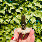 smokey quartz tower sits on a sunstone smokey quartz base. the handcrafted crystal ring holder is held in front of greenery and fits ring sizes 5 and bigger. 