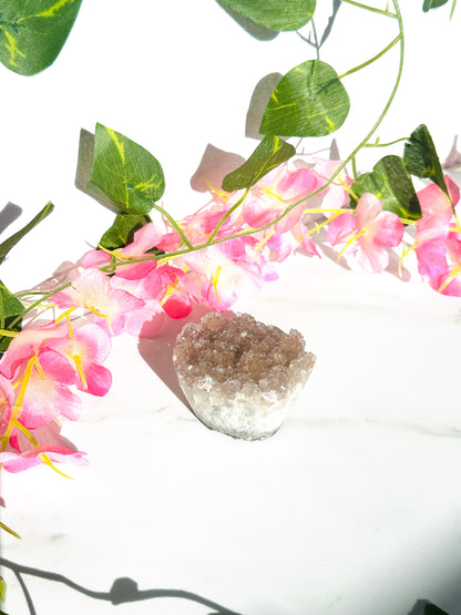 sparkly amethyst cupcake sitting on marble in front of flowers and vines