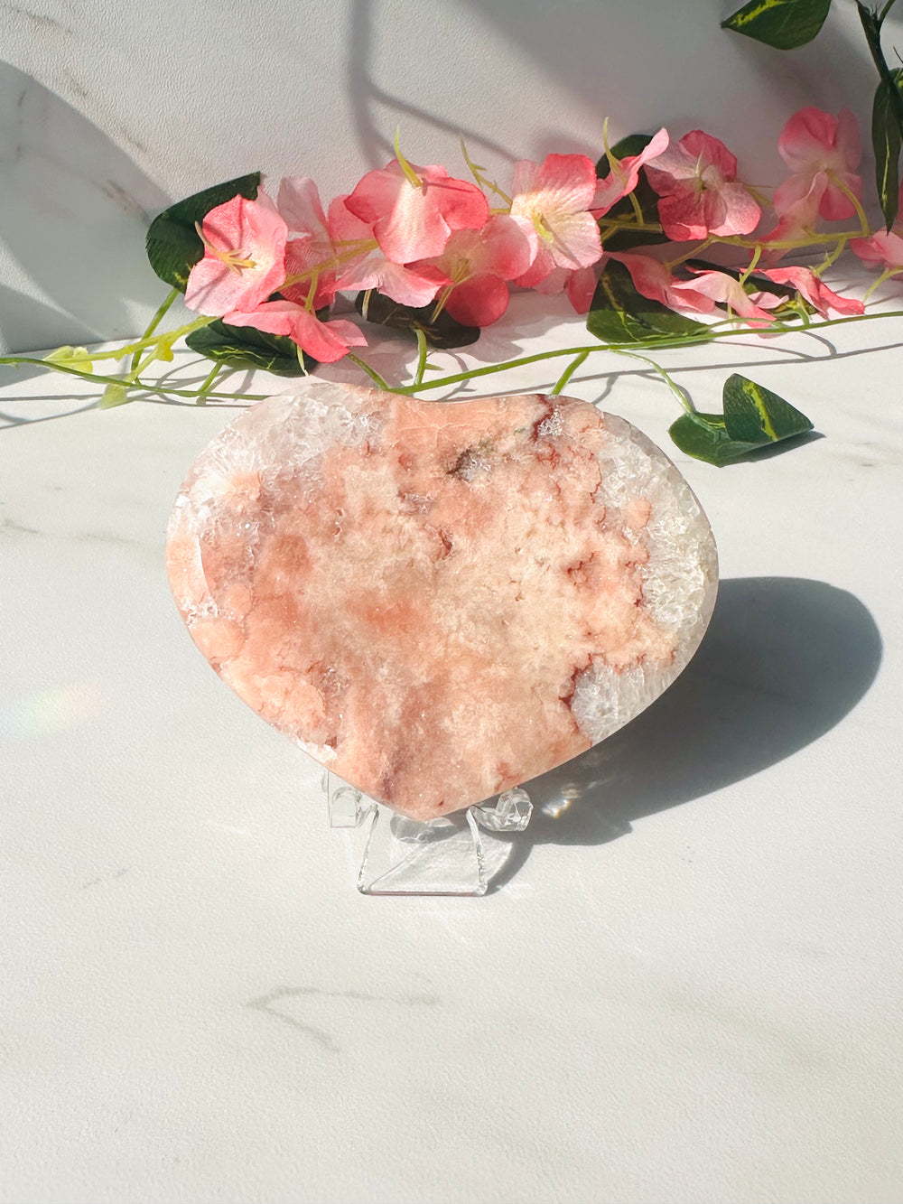 pink flower agate heart with druzy sitting on marble in front of vines