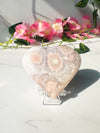 pink flower agate heart sitting on marble in front of vines