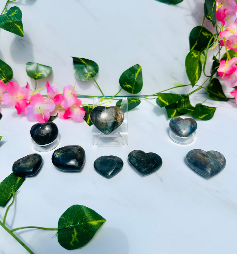 blue and orange flash labradorite hearts on white marble surrounded by greenery and flowers