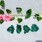 green raw silky velvet malachite free forms sits on white marble surrounded by vines and flowers