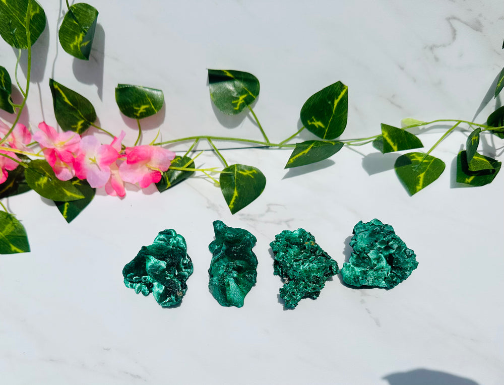 green raw silky velvet malachite free forms sits on white marble surrounded by vines and flowers