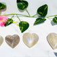 blue flash moonstone hearts sits on white marble with vines and greenery.