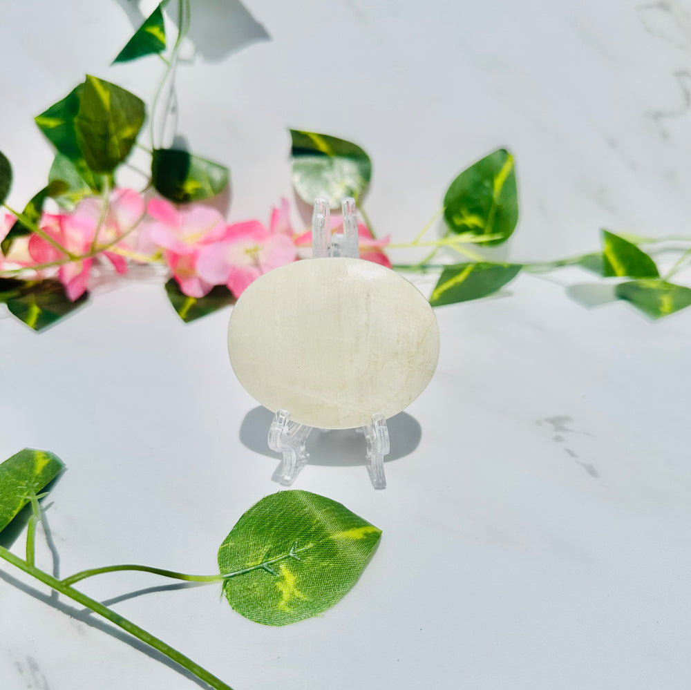 blue flash moonstone sitting on marble with vines and greenery. 