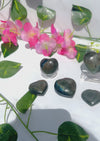 blue and orange flash labradorite hearts on white marble surrounded by greenery and flowers