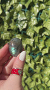 3 beautiful labradorite palm stones are showcased in a womans hand showing off colorful flashes of blue, green, orange, yellow and more.