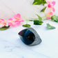 raw rainbow obsidian with polished front sitting on white marble with vines and flowers