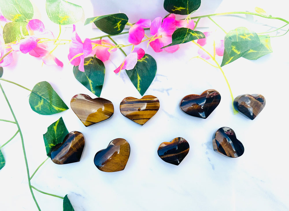 flashy tigers eye hearts on white marble surrounded by greenery and flowers